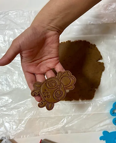 Biscoito de gingerbread recém cortado na mão, sobre a placa de massa aberta