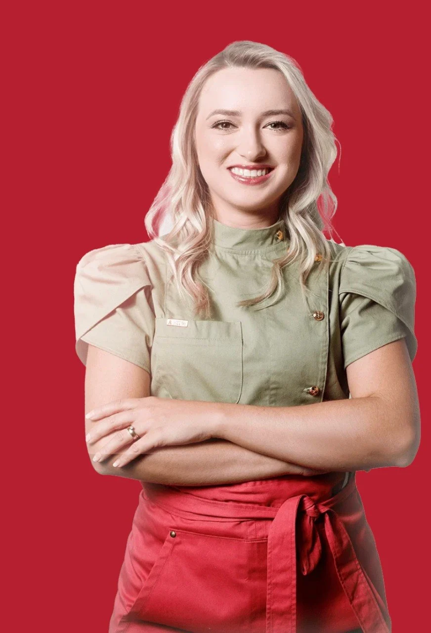 Mari Molina sorrindo, de dólmã verde e avental vermelho, braços cruzados, em fundo vermelho